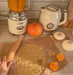 a person is making cookies on a counter with pumpkins and an electric blender