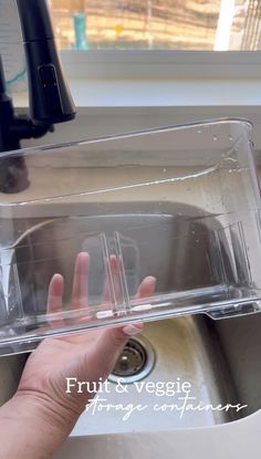 a person's hand is in the sink under a clear plastic container that holds water