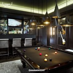 a pool table in the middle of a room with bar lights and chairs around it