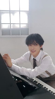 a man sitting at a piano in front of a window with his hands on the keyboard