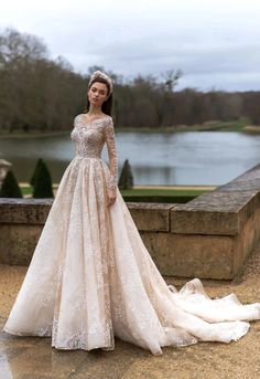 a woman in a wedding dress standing on a stone wall next to a body of water