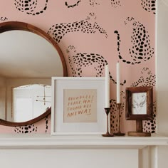 a fireplace with a mirror on top of it next to a framed photograph and candles