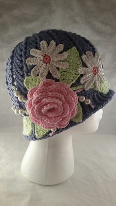 a crocheted hat with flowers is on a white mannequin's head