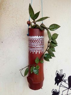 a red vase hanging from a wall with plants in it