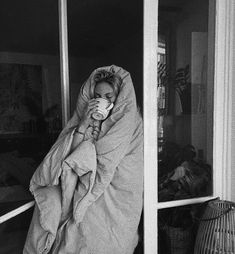 a woman wrapped in a blanket drinking from a cup