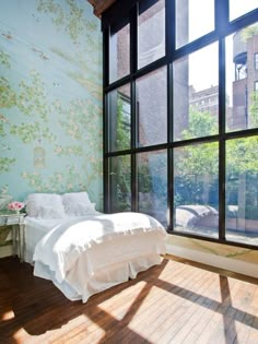 a bedroom with large windows and wallpaper on the walls