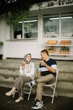 a man and woman sitting on lawn chairs talking to each other in front of a store