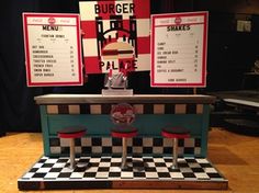 a table with some chairs and menus on the wall behind it in front of a black and white checkerboard floor