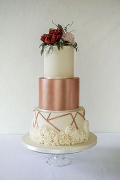 a three tiered wedding cake with roses on the top and gold trimmings