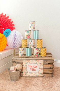 a table with tissue balls, paper fans and tin can tosses on top of it