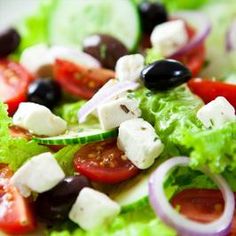 a salad with lettuce, tomatoes, olives and feta cheese on it