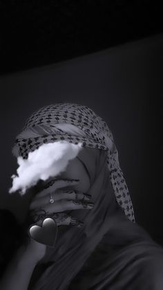 a woman with her face covered by a veil and clouds behind her head, in black and white