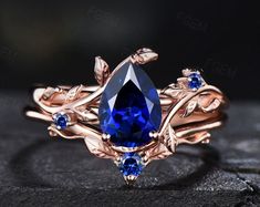 a blue stone surrounded by leaves on top of a black surface with the words gems in gold