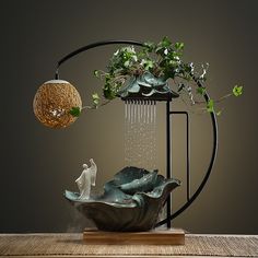 a planter with water flowing from it and a statue in the center on a wooden table