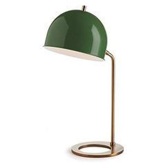 a green lamp on a white surface with a gold base and an oval light fixture