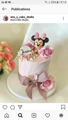 there is a pink cake with minnie mouse on top and flowers in the bottom tier