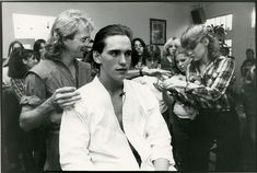 black and white photograph of a man getting his hair cut by another man in the background