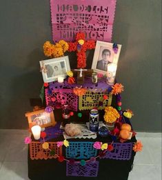 a table with pictures, candles and decorations on it in front of a gray wall