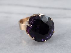 This ring is truly gorgeous! A large and beautiful medium purple amethyst sits in the center, with an amazing cut and vibrant purple color that flickers with bright pops of violet! The stone is expertly cut to really display the stone’s color and sparkle! The classic mid-century mounting is all this stone needs to frame it to perfection! Metal: 14K Yellow Gold Gem: Amethyst 19.81 Carats Gem Measurements: 17.6 mm, Round Ring Size: 7 Marks: "585 FINLAND" Stamped on the inside band Purple Faceted Ring For Formal Occasions, Formal Faceted Purple Ring, Formal Purple Faceted Ring, Faceted Purple Amethyst Ring For Formal Occasions, Formal Faceted Purple Amethyst Ring, Formal Purple Amethyst Ring With Round Stone, Round Amethyst Ring With Diamond Cut, Faceted Purple Amethyst Ring Fine Jewelry, Elegant Purple Amethyst Ring With Large Stone