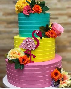 a multi layer cake decorated with flowers and a flamingo on the top is brightly colored