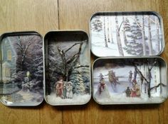 four tins with different scenes on them sitting on a wooden table next to each other