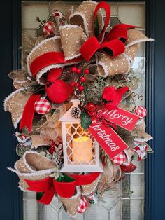 a christmas wreath hanging on the front door with a lit candle and red ribbon around it