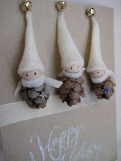 three little gnomes are hanging on the wall with pine cones and acorns