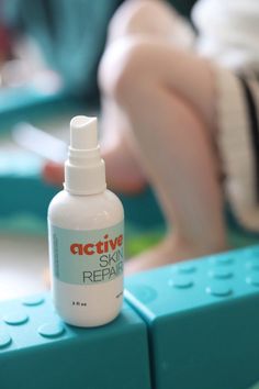 a bottle of active skin repair sitting on top of a blue lego block with a child in the background