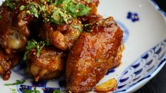 some chicken wings with sauce and herbs on a blue and white plate, ready to be eaten