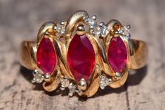 The Sullana Vintage Lab Grown Ruby and Diamond Ring. The ring Features three central rubies in a unique vintage patterned top with round diamonds set opposite each other on the ends. The ring is crafted in yellow gold and is a finger size 7 yet could be adjusted to any size. Each piece has been hand selected and meticulously identified and graded by a Graduate Gemologist who has been awarded a degree by the Gemological Institute of America (GIA). Please visit our Shop's About Page or our website Luxury Red Three Stone Jewelry, Luxury Red Three-stone Jewelry, Fine Jewelry Red Diamond Three Stone Ring, Elegant Three-stone Red Diamond Ring, Elegant Three Stone Red Diamond Ring, Three Stone Ruby Ring In Yellow Gold, Elegant Red Three-stone Diamond Ring, Gold Ruby Ring With Three Stones, Elegant Red Three Stone Diamond Ring