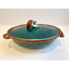 a green and brown bowl sitting on top of a white table