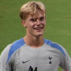 a young man holding a tennis racquet on top of a field