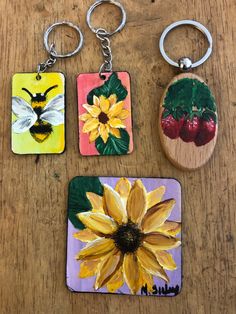 four different key chains with pictures of flowers and bees on them, one has a sunflower