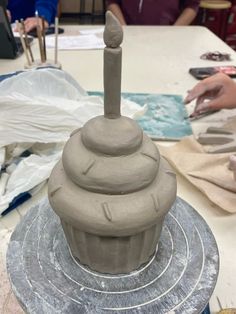 a clay sculpture is sitting on top of a table with people working in the background