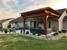 a patio with an attached pergolan and lights on the roof, in front of a house