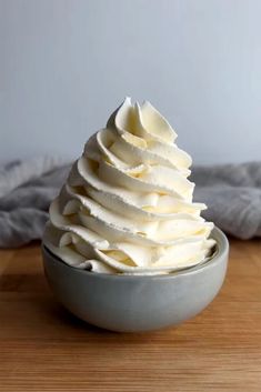 a bowl filled with whipped cream on top of a wooden table