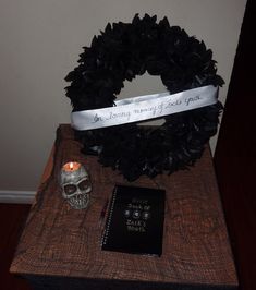 a wreath, book and candle are on a table next to a skull head with a ribbon around it