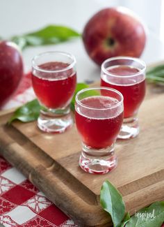 three glasses of apple cider on a cutting board