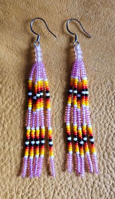 two pairs of colorful beaded earrings sitting on top of a bed