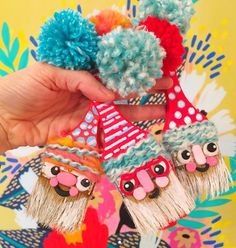 a person holding up two small pom poms in front of a colorful background