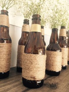 there are several bottles with flowers in them on the table together and tied to burlap