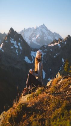 a woman sitting on top of a mountain looking at the mountains