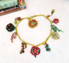 a necklace with beads and charms is laying on a table next to a stack of books