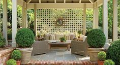 an outdoor living area with chairs, tables and potted plants on either side of the gazebo