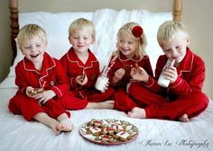 three children in red pajamas eating cookies and milk