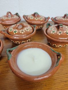 a table topped with brown pottery covered in white candles