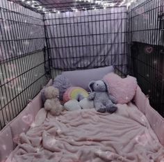 there are stuffed animals in the small caged bed with pink sheets and blankets on it