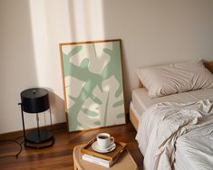 a bedroom with a bed, nightstand and coffee cup on the table next to it