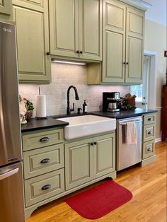 a kitchen with green cabinets and stainless steel appliances, including a dishwasher on the counter