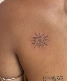 the back of a man's chest with a sun tattoo on his left side